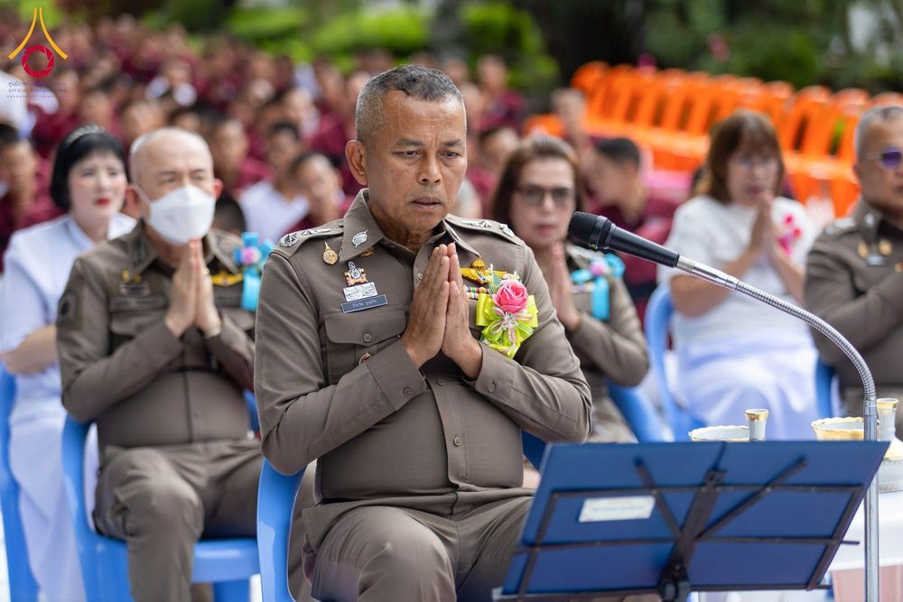 เจ้าหน้าที่ตำรวจชายในเครื่องแบบสีกากีพนมมือไหว้ในพิธีทางศาสนา