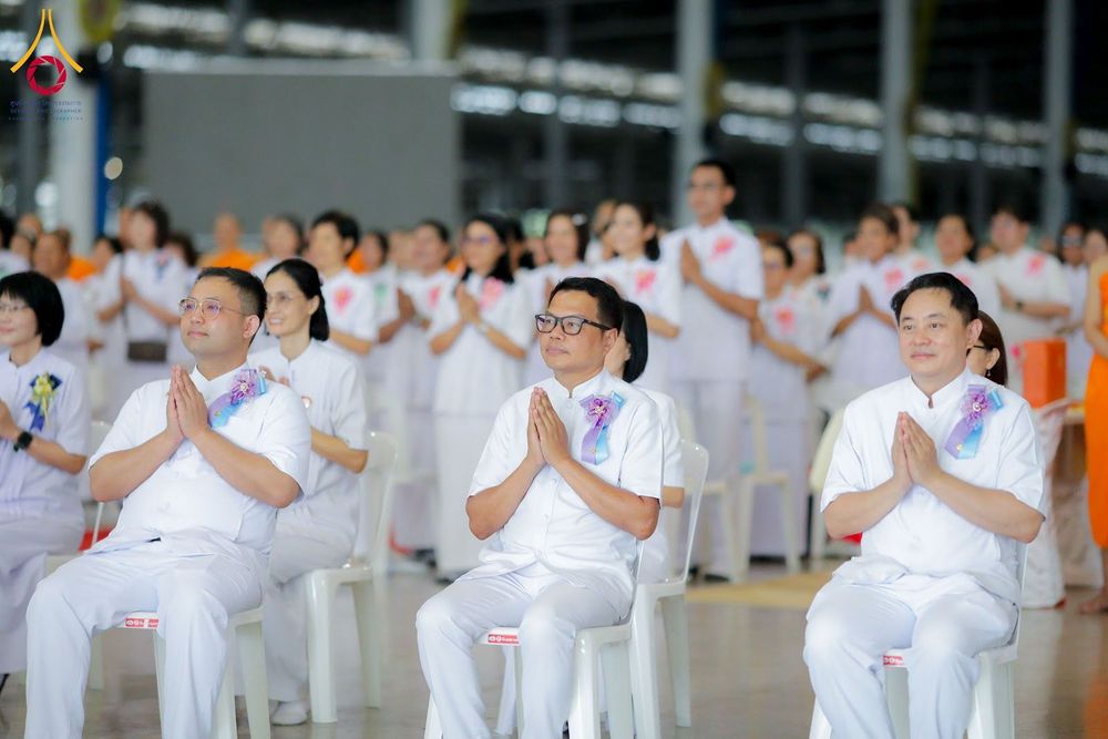 กลุ่มพุทธศาสนิกชนสวมชุดขาวนั่งพนมมือร่วมพิธีทางศาสนาภายในสภาธรรมกายสากล