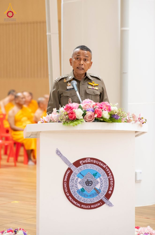 เจ้าหน้าที่ตำรวจยืนกล่าวรายงานที่โพเดียมประดับดอกไม้ในพิธีปิดโครงการบรรพชาพัฒนาคุณธรรม