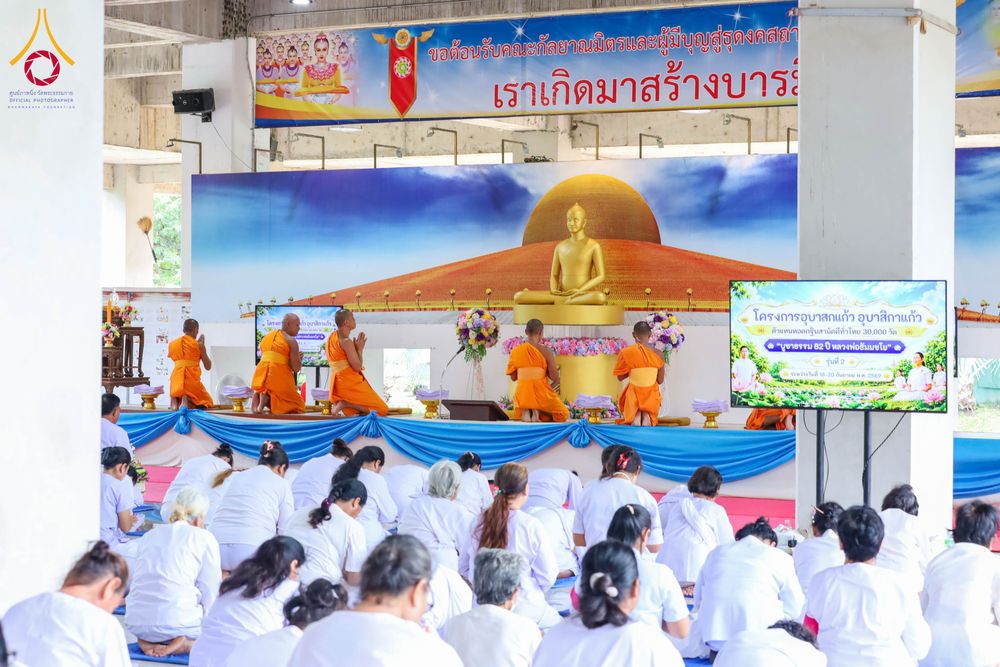 พระภิกษุและผู้เข้าร่วมโครงการในชุดขาวกำลังประกอบกิจกรรมทางศาสนาภายในอาคาร
