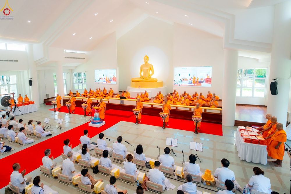 คณะสงฆ์และพุทธศาสนิกชนร่วมพิธีทำบุญภายในอาคารปฏิบัติธรรมที่มีพระพุทธรูปประดิษฐานอยู่ด้านหน้า