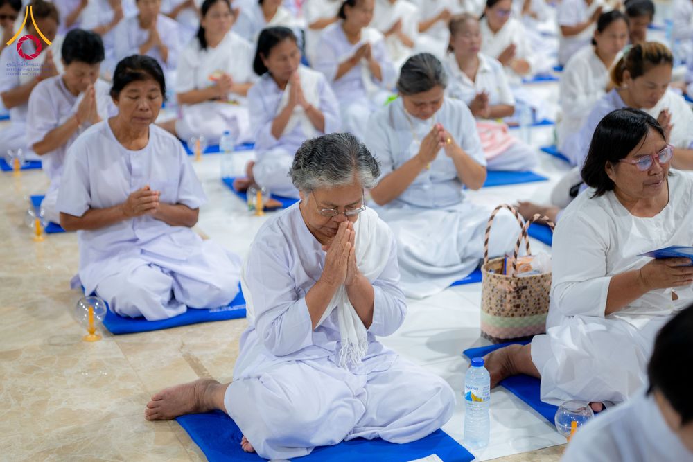 กลุ่มคนสวมชุดขาวนั่งพนมมือบนเบาะรองนั่งเพื่อปฏิบัติธรรม
