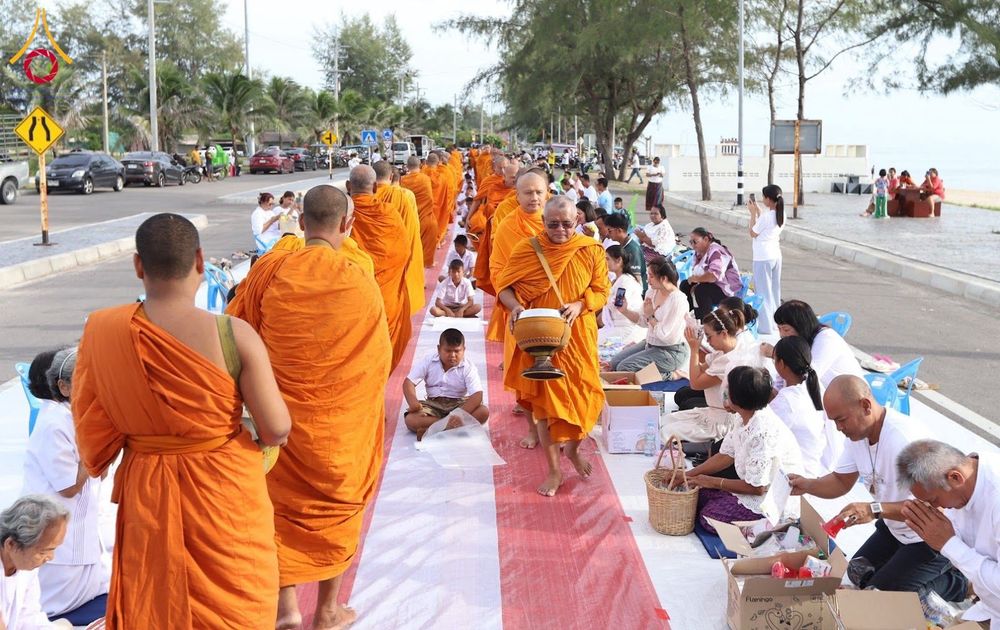พระสงฆ์เดินรับบิณฑบาตจากประชาชนที่นั่งรอใส่บาตรริมถนนเลียบชายหาด
