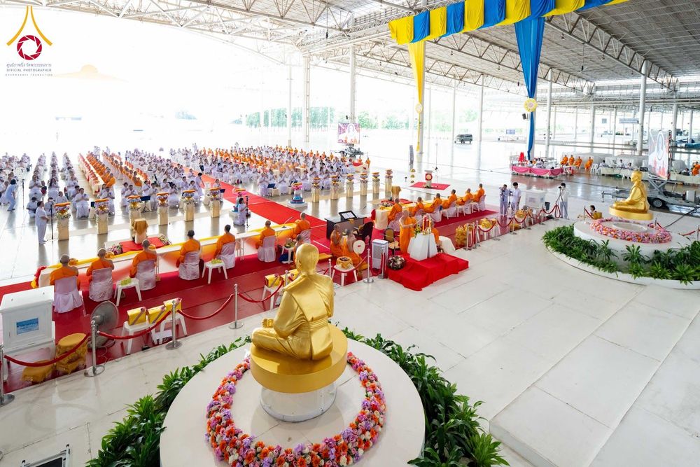 พระภิกษุและสาธุชนนั่งเรียงแถวเข้าร่วมพิธีทางศาสนาภายในอาคารขนาดใหญ่ที่มีรูปหล่อทองคำประดิษฐานอยู่