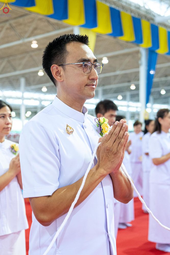 ชายสวมชุดขาวพนมมือถือสายสิญจน์ในพิธีทางศาสนา