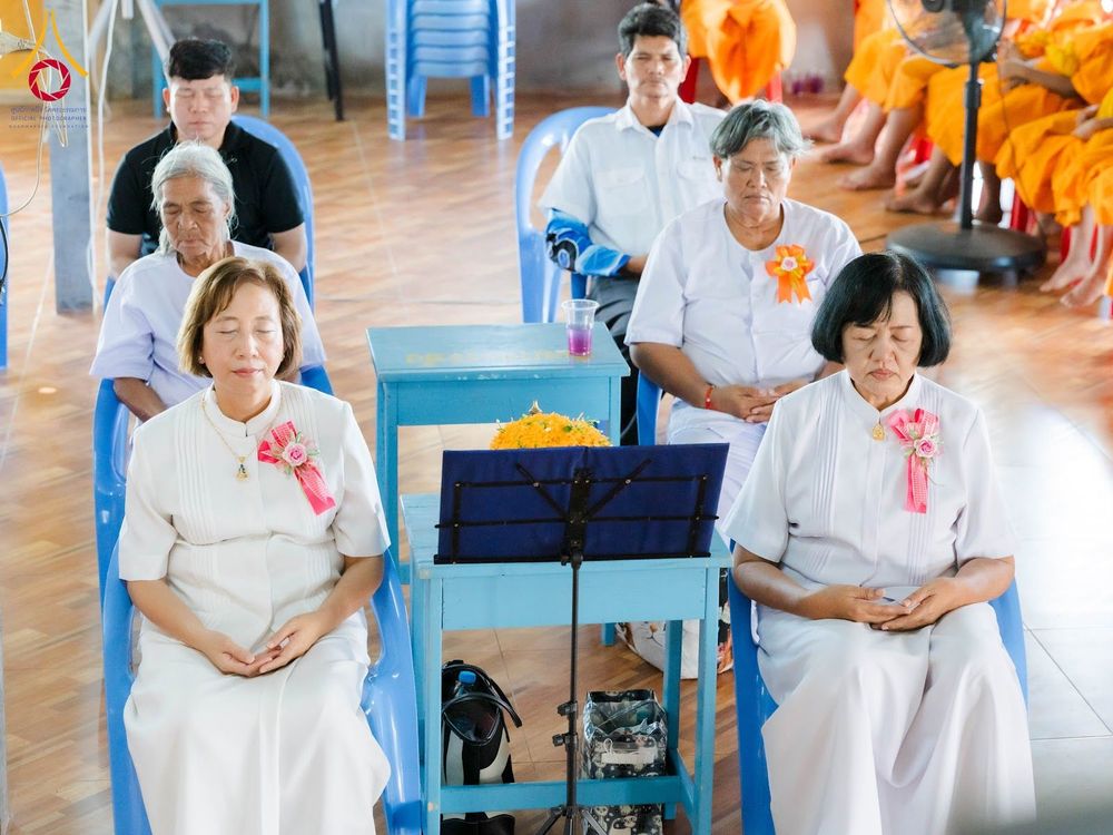 กลุ่มคนสวมชุดขาวนั่งทำสมาธิในพิธีทางศาสนาภายในอาคาร