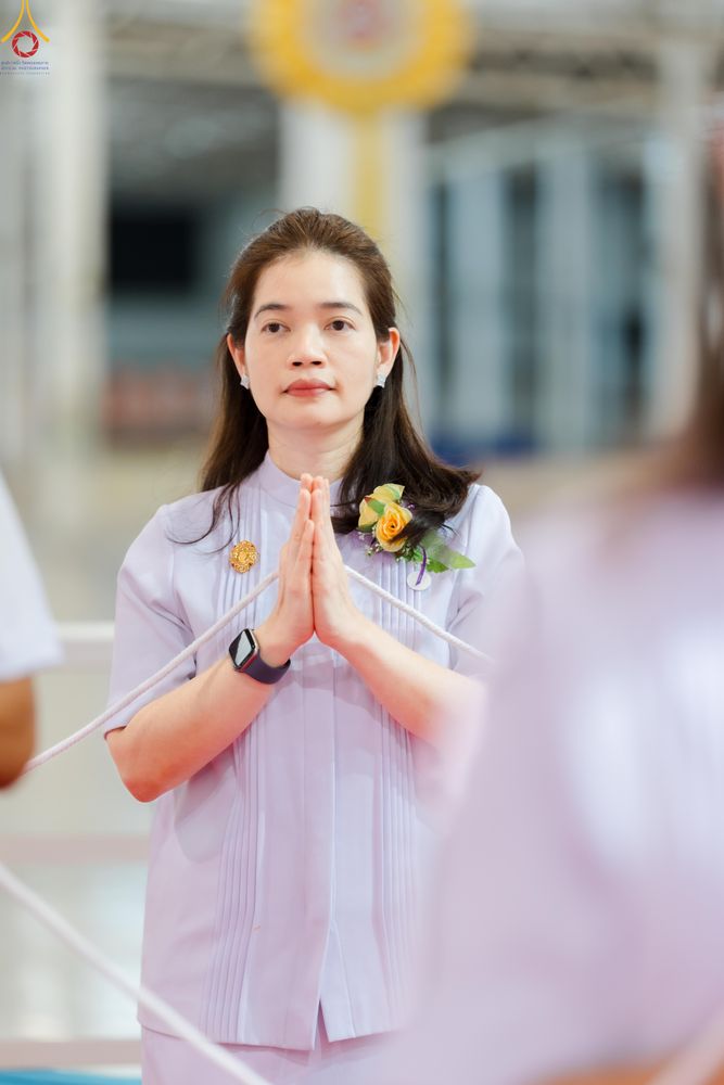 หญิงสาวสวมชุดสีขาวพนมมือด้วยท่าทางสำรวมในพิธีกรรมทางศาสนา