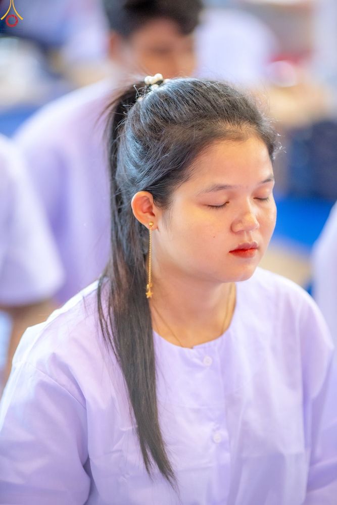 หญิงสาวสวมชุดสีขาวกำลังหลับตาทำสมาธิอย่างสงบ