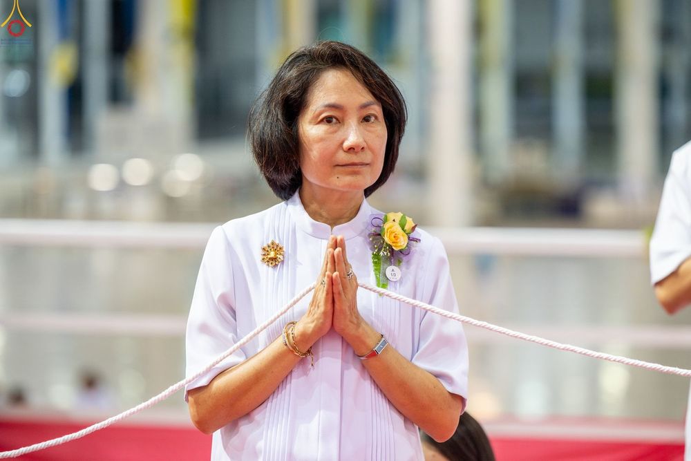 สุภาพสตรีผมสั้นสวมชุดสีขาวพนมมืออย่างสงบในพิธีทางศาสนา