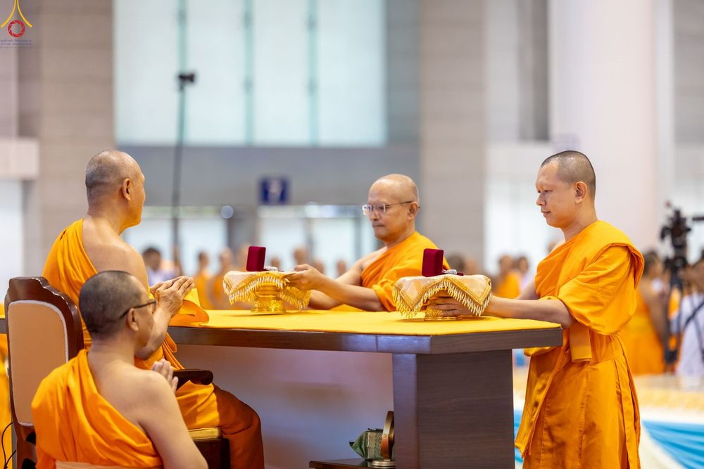 พระภิกษุสงฆ์กำลังประกอบพิธีมอบพระของขวัญบนพานทองภายในอาคาร