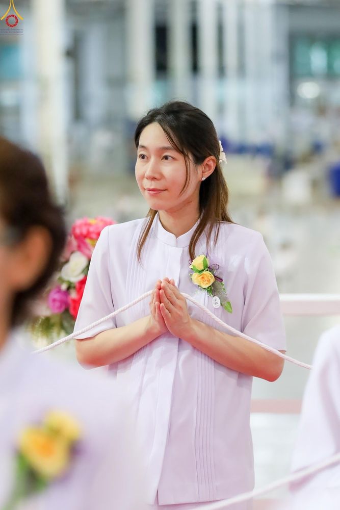 หญิงสาวสวมชุดสีขาวพนมมือถือสายสิญจน์ด้วยความตั้งใจ