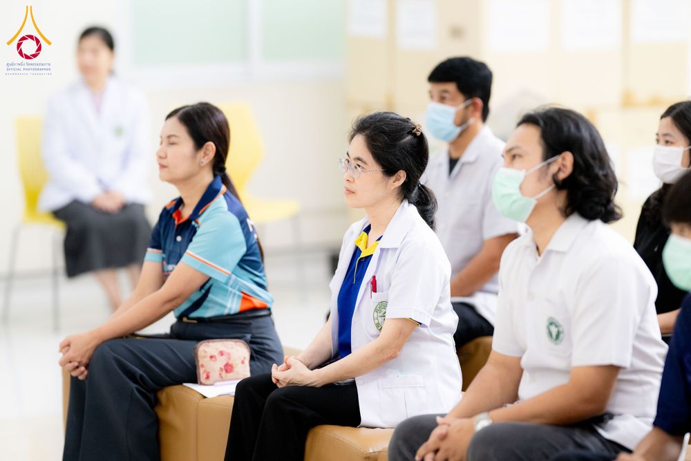 กลุ่มบุคลากรทางการแพทย์และผู้เข้าร่วมงานนั่งเรียงแถวภายในอาคาร