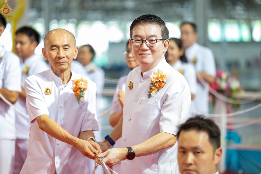 ชายสองคนสวมชุดสีขาวกำลังถืออุปกรณ์ประกอบพิธีจุดเทียนใจ ไฟนิรันดร์ อนันตชัย