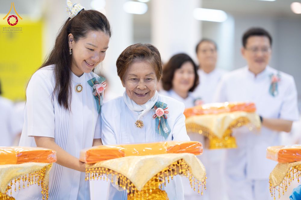กลุ่มคนในชุดสีขาวกำลังถือพานพุ่มผ้าไตรในพิธีทางศาสนา