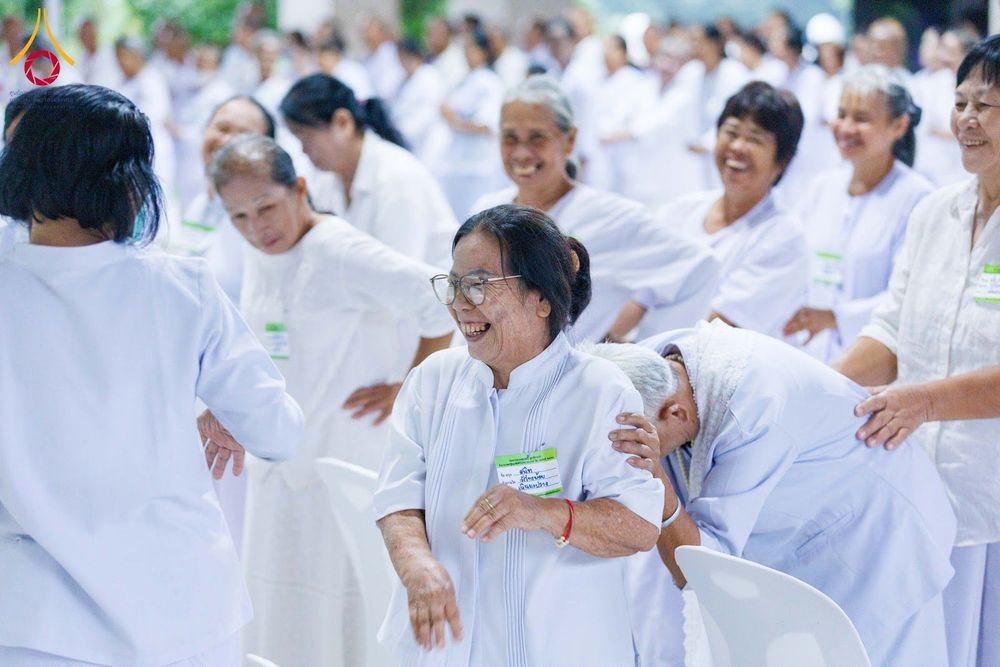 กลุ่มผู้หญิงสวมชุดสีขาวกำลังทำกิจกรรมกลุ่มร่วมกันด้วยความสนุกสนานและมีรอยยิ้ม