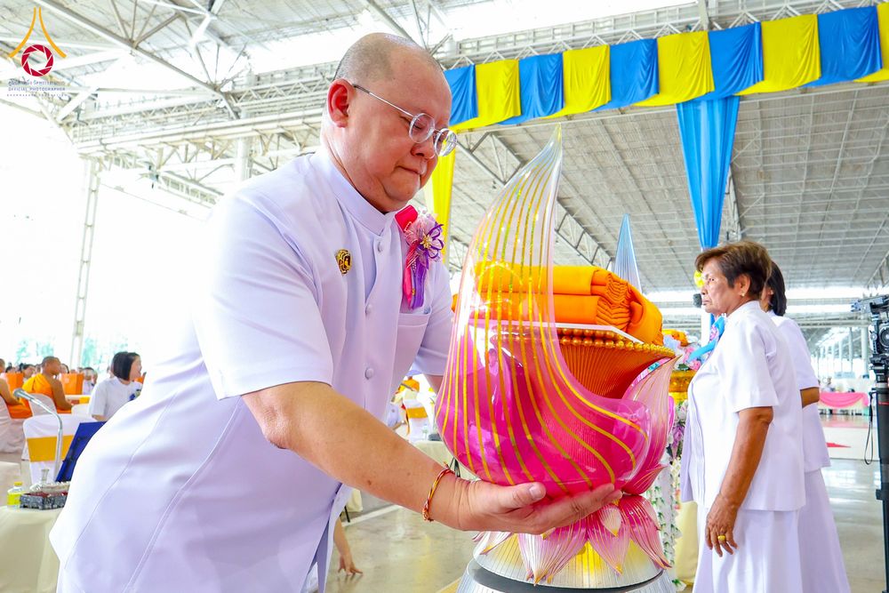 ชายสวมชุดขาวประคองพานพุ่มผ้าไตรจีวรในพิธีทอดผ้าป่า