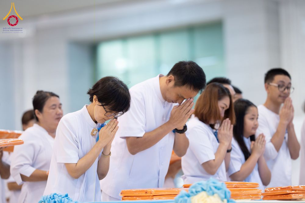 กลุ่มคนสวมชุดขาวพนมมือไหว้ในพิธีทางศาสนา
