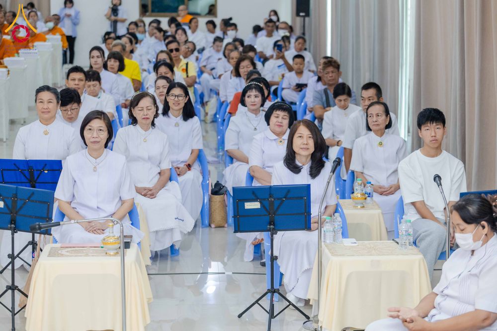 กลุ่มผู้เข้าร่วมสัมมนาสวมชุดสีขาวนั่งเรียงแถวภายในห้องประชุมเพื่อฟังการบรรยาย