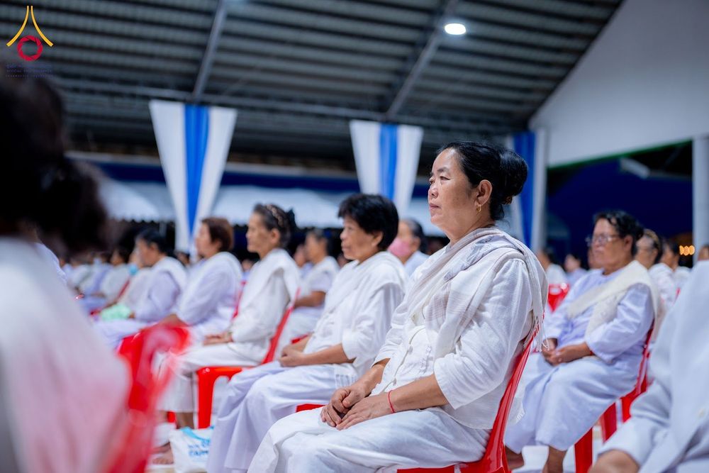 กลุ่มอุบาสิกาสวมชุดสีขาวนั่งฟังธรรมภายในอาคารปฏิบัติธรรม