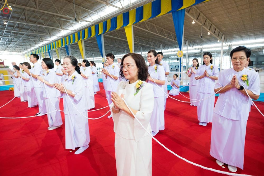 กลุ่มคนสวมชุดขาวพนมมือถือสายสิญจน์ในพิธีกรรมทางศาสนา