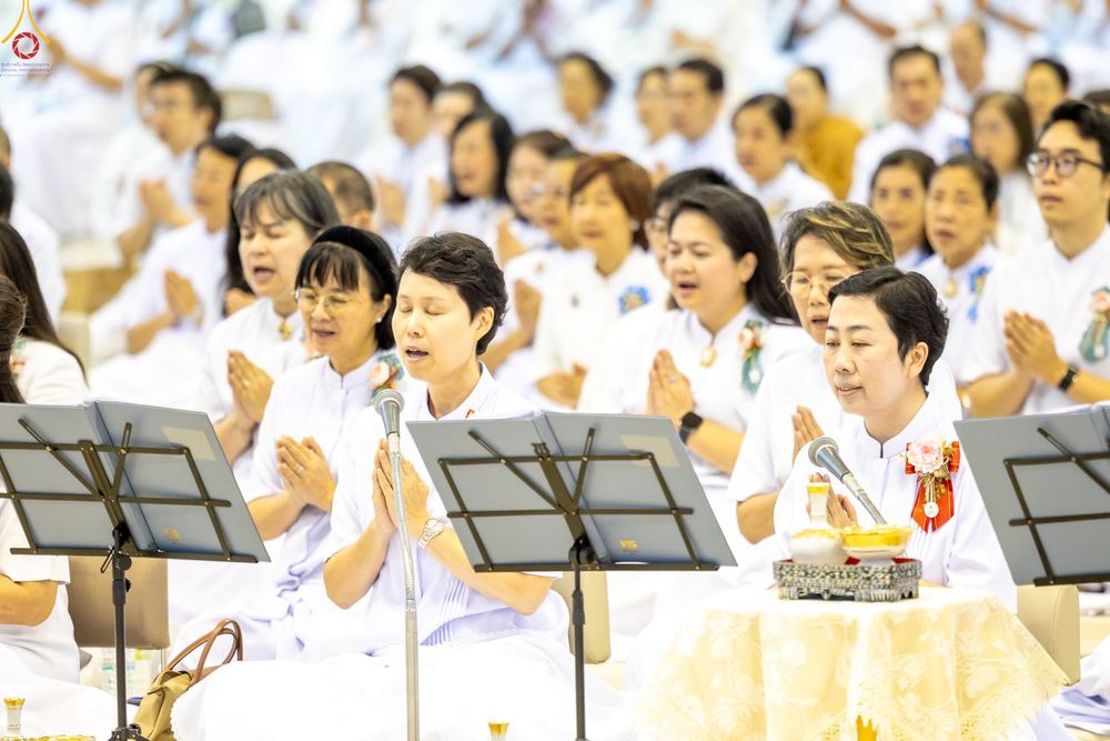 กลุ่มพุทธศาสนิกชนสวมชุดขาวนั่งพนมมือสวดมนต์ในพิธีทางศาสนา
