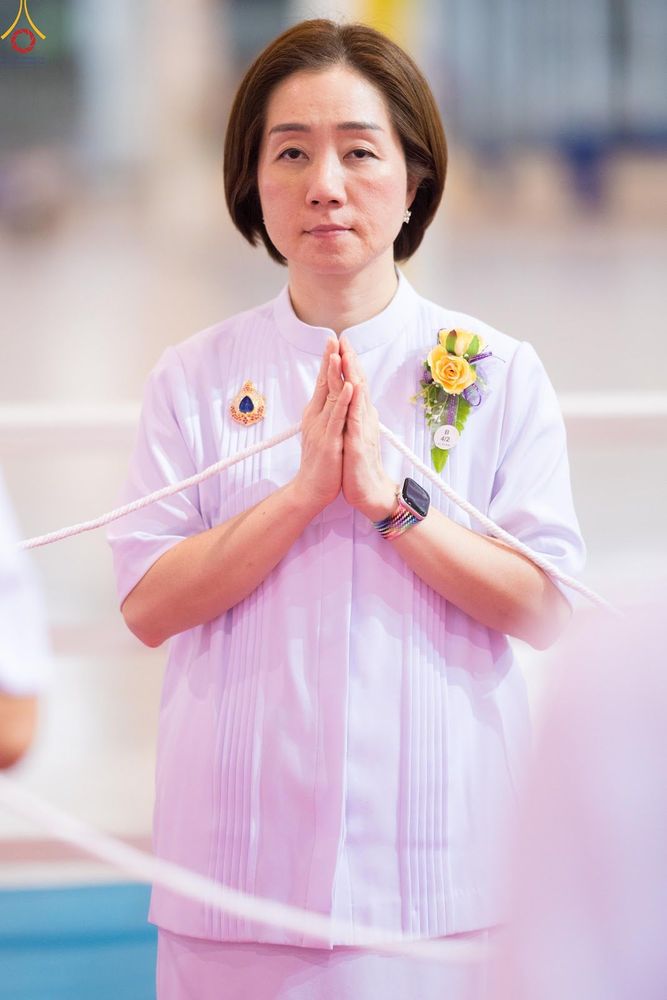 หญิงสาวสวมชุดสีขาวพนมมือถือสายสิญจน์ในพิธีการ