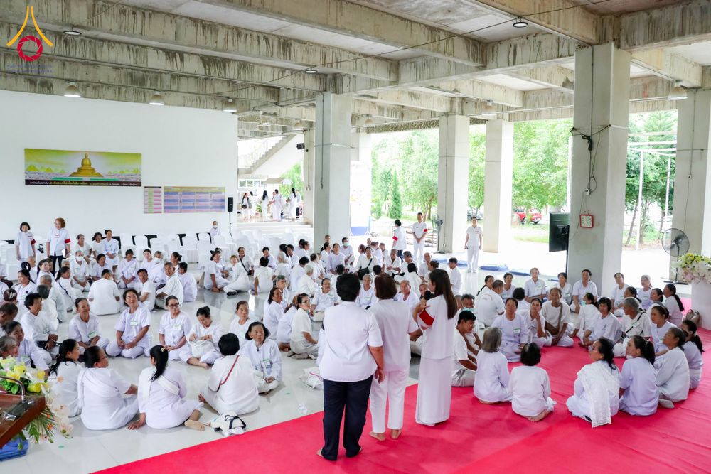กลุ่มผู้เข้าร่วมโครงการอบรมสวมชุดสีขาวนั่งล้อมวงทำกิจกรรมภายในอาคาร