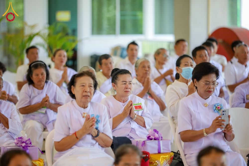 กลุ่มอุบาสิกาในชุดขาวนั่งพนมมือร่วมกิจกรรมอบรมในอาคาร