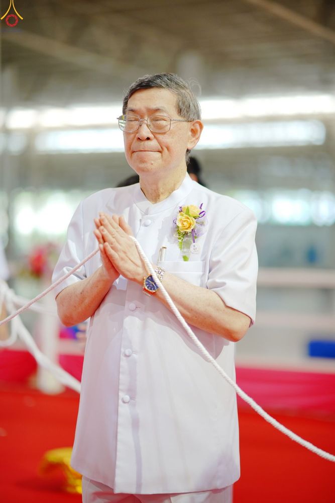 ชายสูงวัยสวมชุดสีขาวพนมมืออย่างสงบในพิธีการ