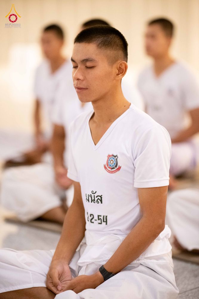 นักเรียนนายสิบตำรวจผมสั้นสวมเสื้อยืดสีขาวนั่งหลับตาทำสมาธิ