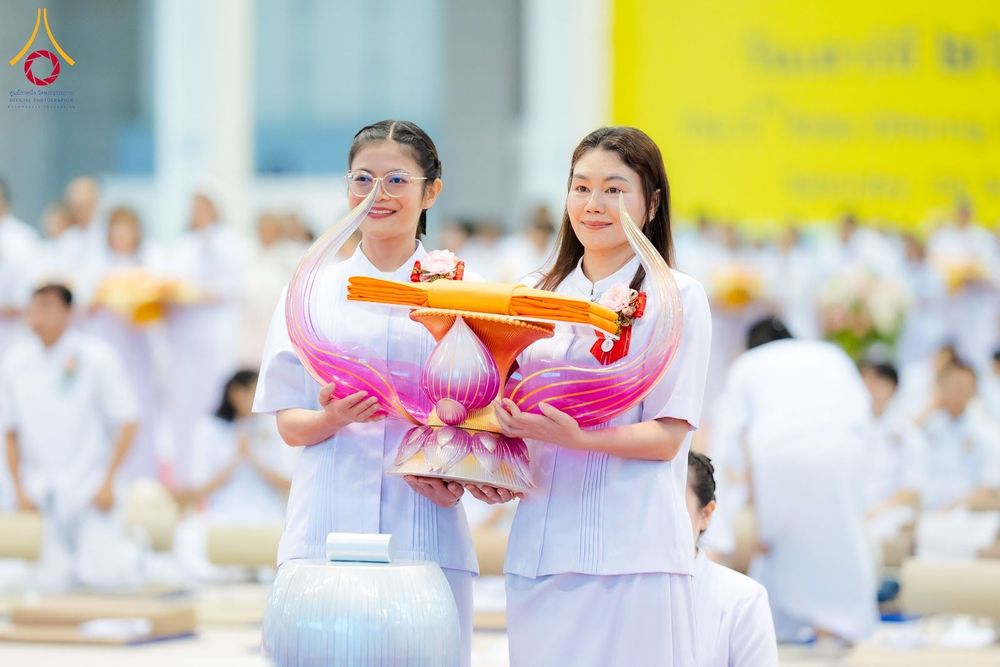 หญิงสองคนสวมชุดขาวถือพานผ้าไตรในพิธีทางศาสนา
