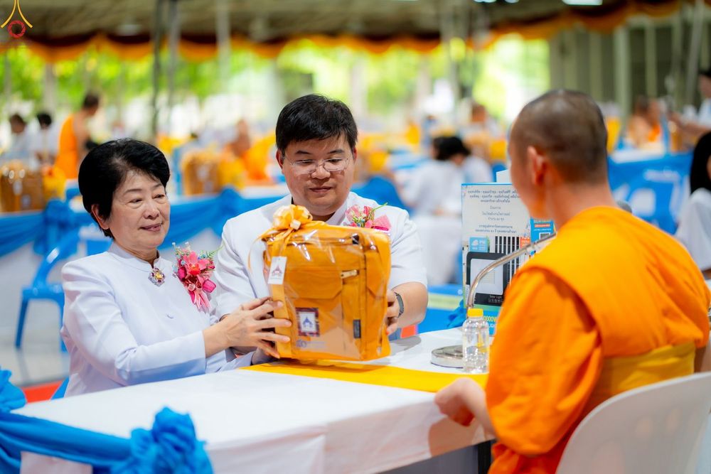ชายและหญิงสวมชุดสีขาวกำลังถวายสังฆทานแด่พระภิกษุสงฆ์ในงานพิธีทางศาสนา