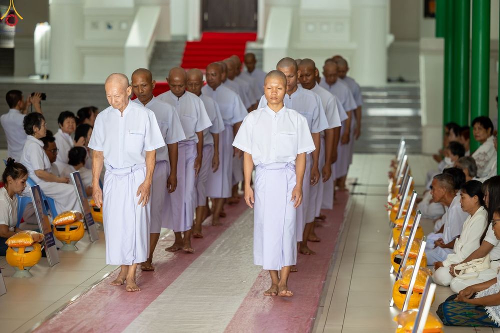 กลุ่มชายในชุดสีขาวเดินเรียงแถวเข้าสู่พิธีอุปสมบทภายในโบสถ์