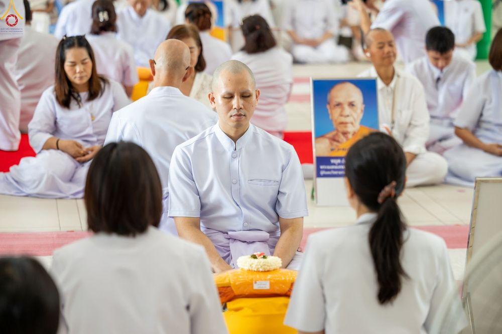 กลุ่มคนสวมชุดสีขาวนั่งสมาธิในพิธีบรรพชาอุปสมบทภายในโบสถ์