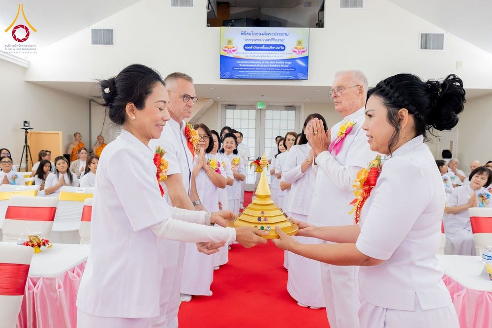 กลุ่มคนในชุดสีขาวกำลังร่วมพิธีอัญเชิญพระบรมสารีริกธาตุภายในวัด