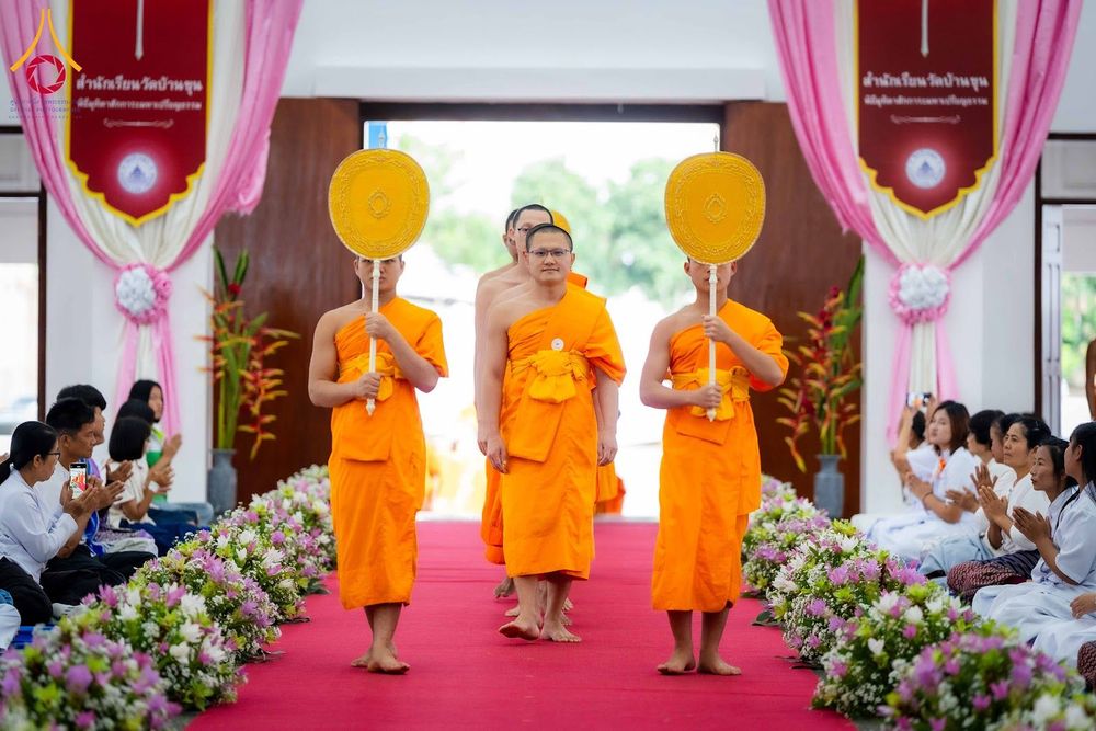พระภิกษุสงฆ์เดินแถวเข้าสู่พิธีมุทิตาสักการะภายในอาคารที่มีการตกแต่งด้วยดอกไม้และพรมสีแดง