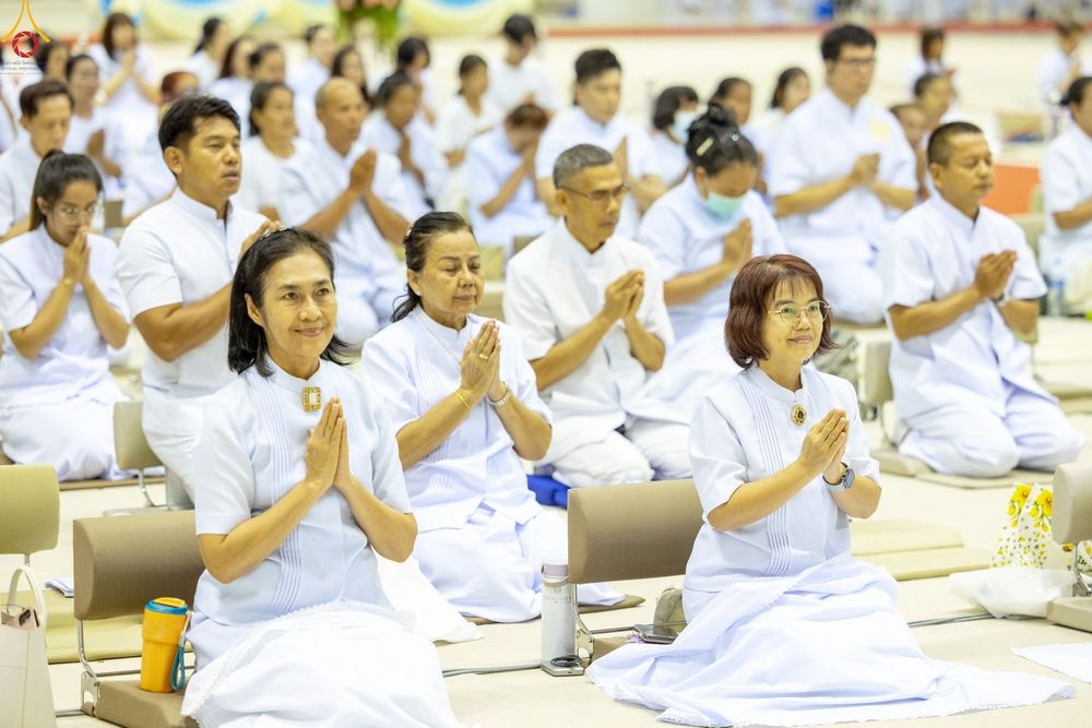 กลุ่มคนสวมชุดสีขาวนั่งพนมมือปฏิบัติธรรมภายในห้องโถง