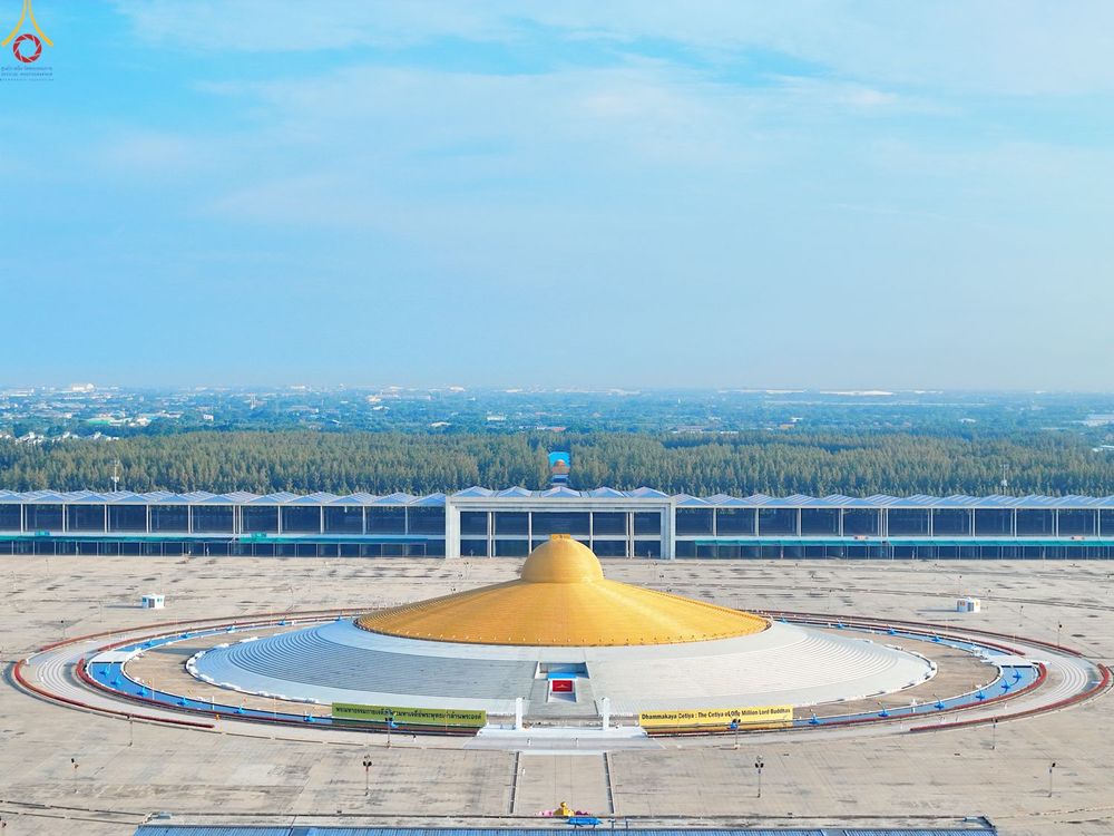 มหาธรรมกายเจดีย์สีทองรูปทรงโดมตั้งอยู่หน้าอาคารสภาธรรมกายสากลในพื้นที่โล่งกว้าง