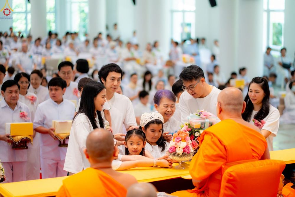 กลุ่มพุทธศาสนิกชนสวมชุดสีขาวกำลังถวายพานดอกไม้แด่พระภิกษุสงฆ์ในงานบุญ