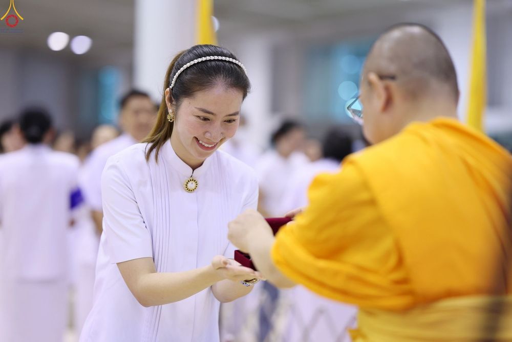 หญิงสาวชุดขาวกำลังรับมอบพระของขวัญจากพระภิกษุสงฆ์