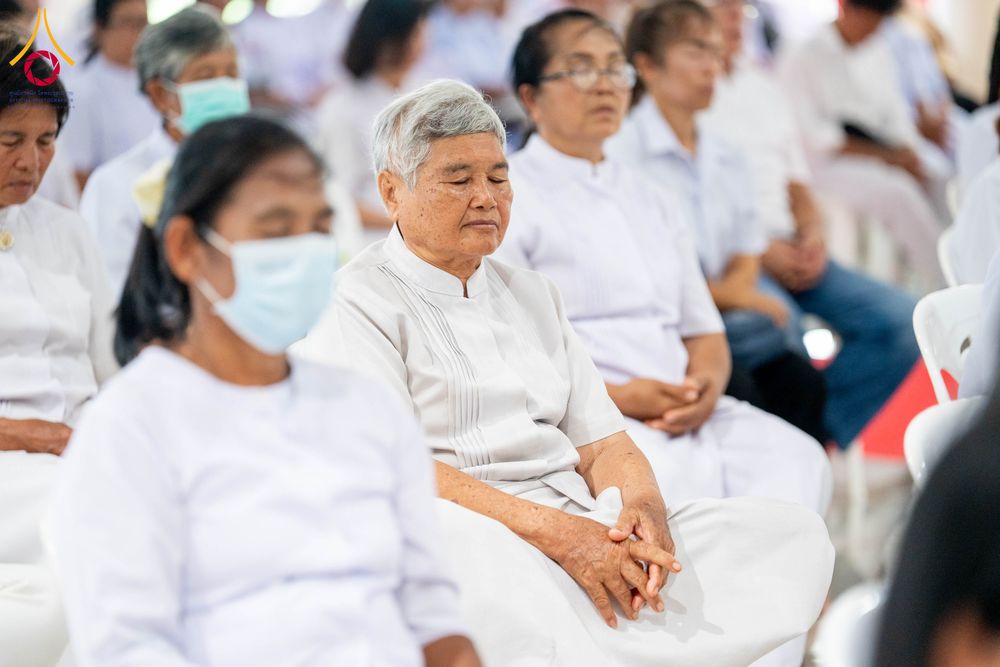 กลุ่มคนสวมชุดสีขาวนั่งสมาธิในพิธีทางศาสนา