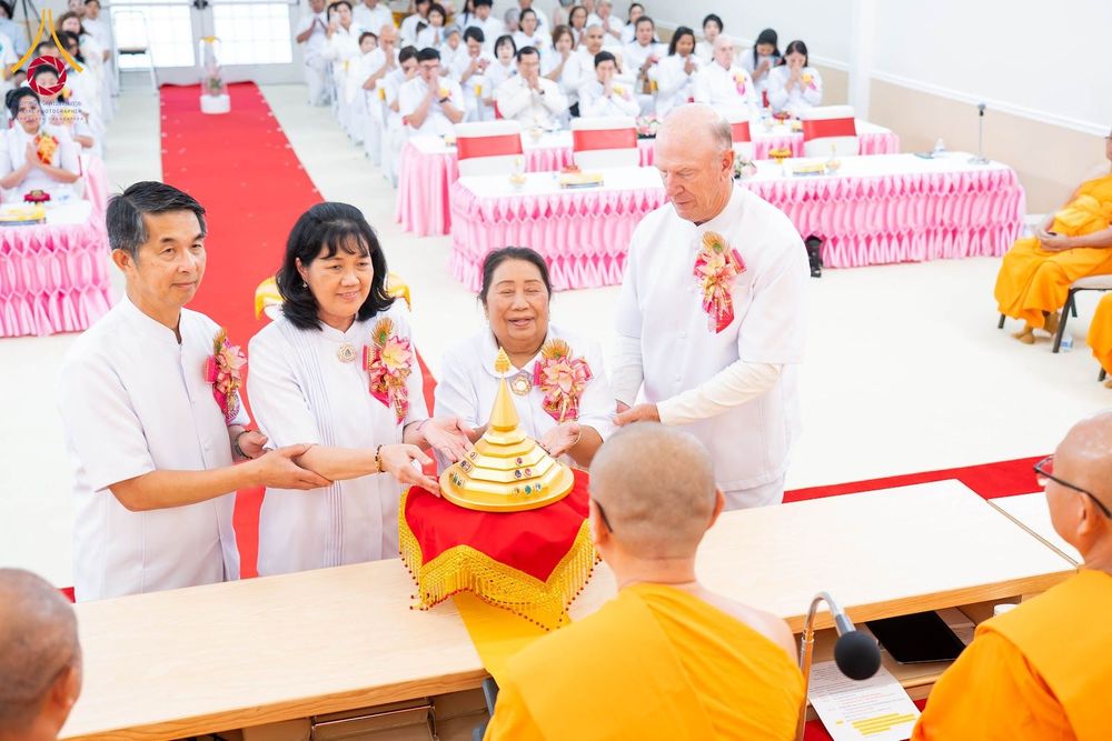 กลุ่มคนในชุดขาวกำลังประกอบพิธีอัญเชิญพระบรมสารีริกธาตุต่อหน้าพระภิกษุสงฆ์ในงานพิธีทางศาสนา