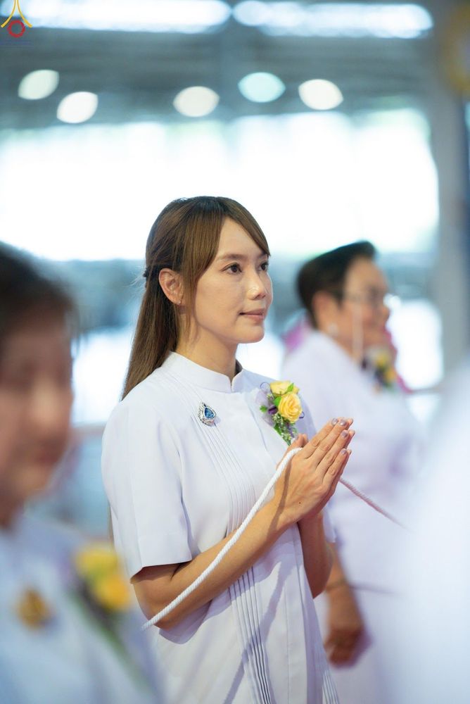 หญิงสาวสวมชุดขาวพนมมือถือสายสิญจน์ในพิธีกรรมทางศาสนา