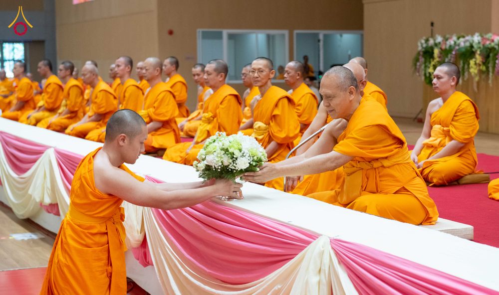 พระภิกษุสงฆ์รับพานดอกไม้จากผู้เข้าร่วมโครงการบรรพชาท่ามกลางพระภิกษุรูปอื่นที่นั่งเรียงแถว