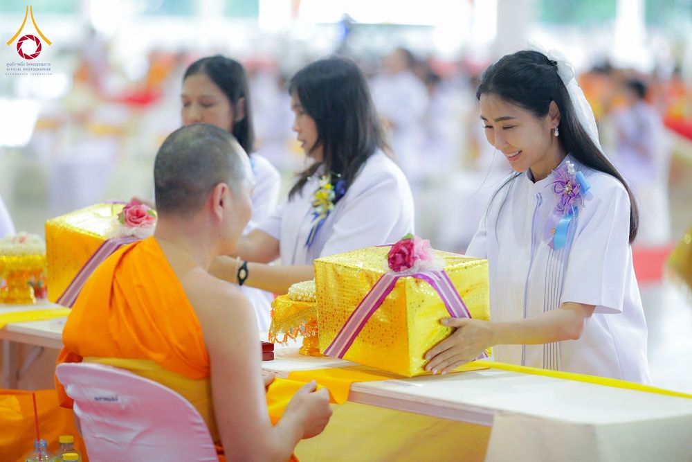 หญิงสาวชุดขาวประเคนกล่องของขวัญสีทองแด่พระภิกษุสงฆ์ในพิธีทางศาสนา