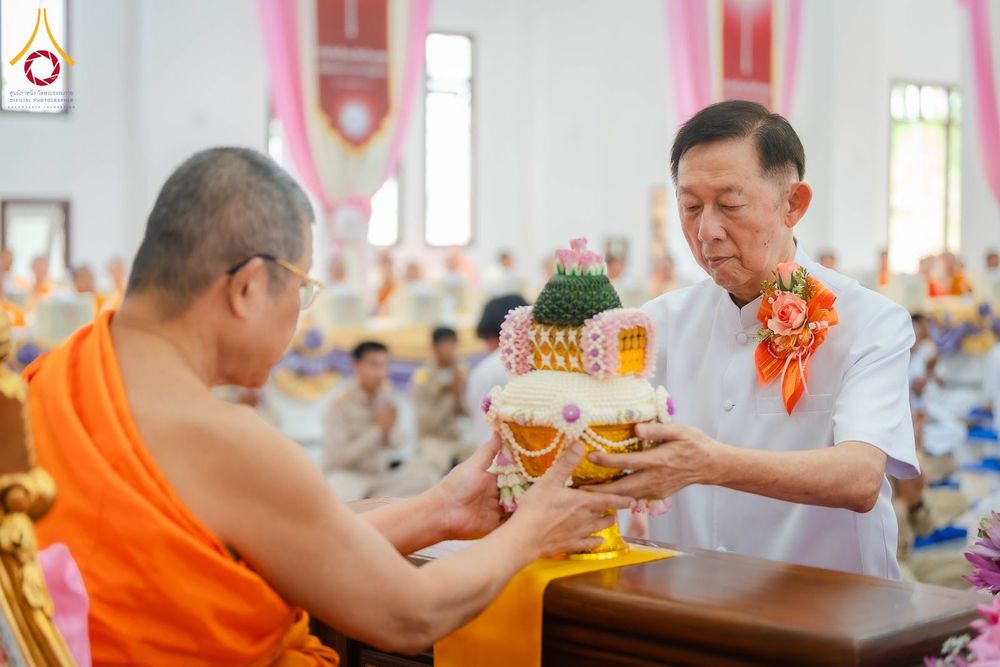 ชายสวมชุดขาวประคองพานพุ่มดอกไม้ถวายแด่พระภิกษุสงฆ์ในพิธีทางศาสนา