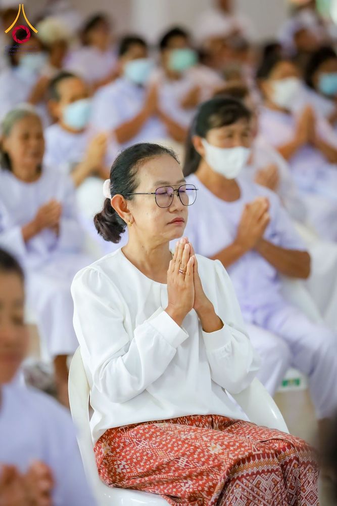 กลุ่มผู้เข้าร่วมโครงการปฏิบัติธรรมสวมชุดสีขาวนั่งพนมมือด้วยความสงบ