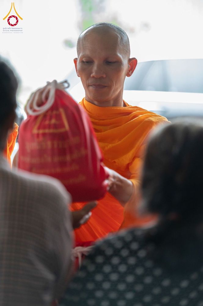 พระภิกษุกำลังส่งมอบถุงยังชีพสีแดงให้กับประชาชน