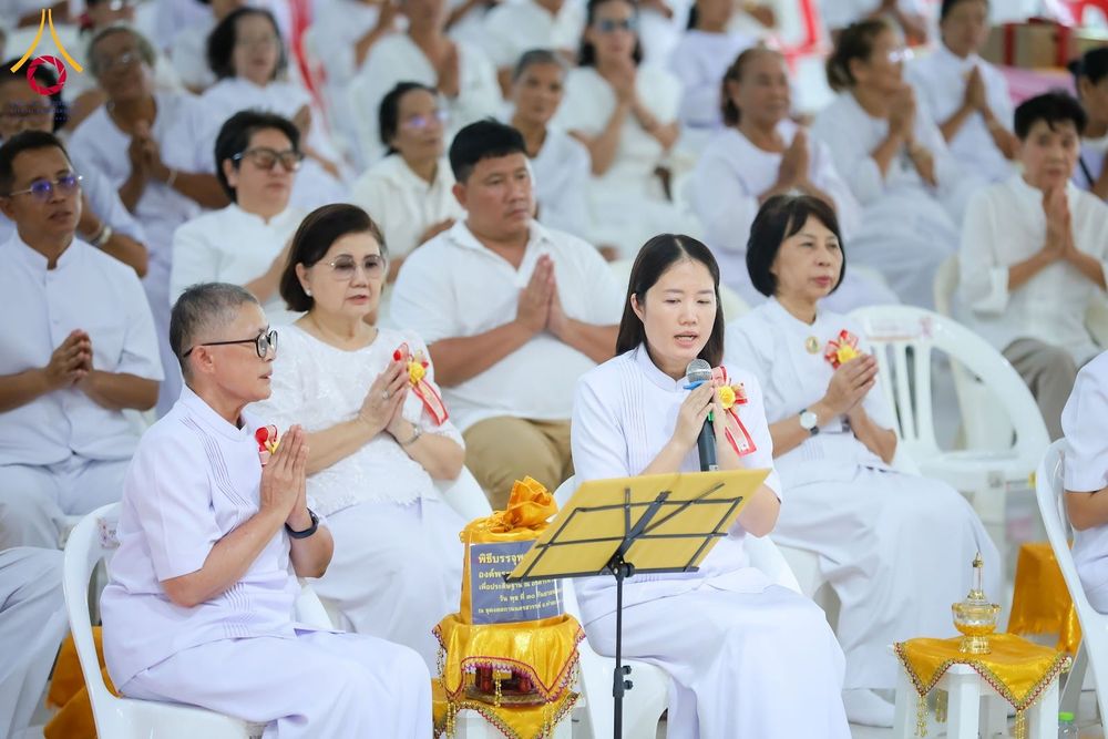 กลุ่มคนสวมชุดขาวนั่งพนมมือร่วมพิธีทางศาสนาภายในอาคาร