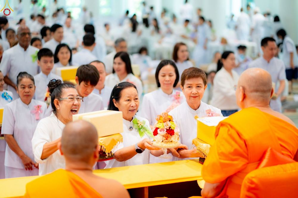 กลุ่มพุทธศาสนิกชนสวมชุดสีขาวกำลังถวายสังฆทานแด่พระภิกษุสงฆ์ในงานบุญ